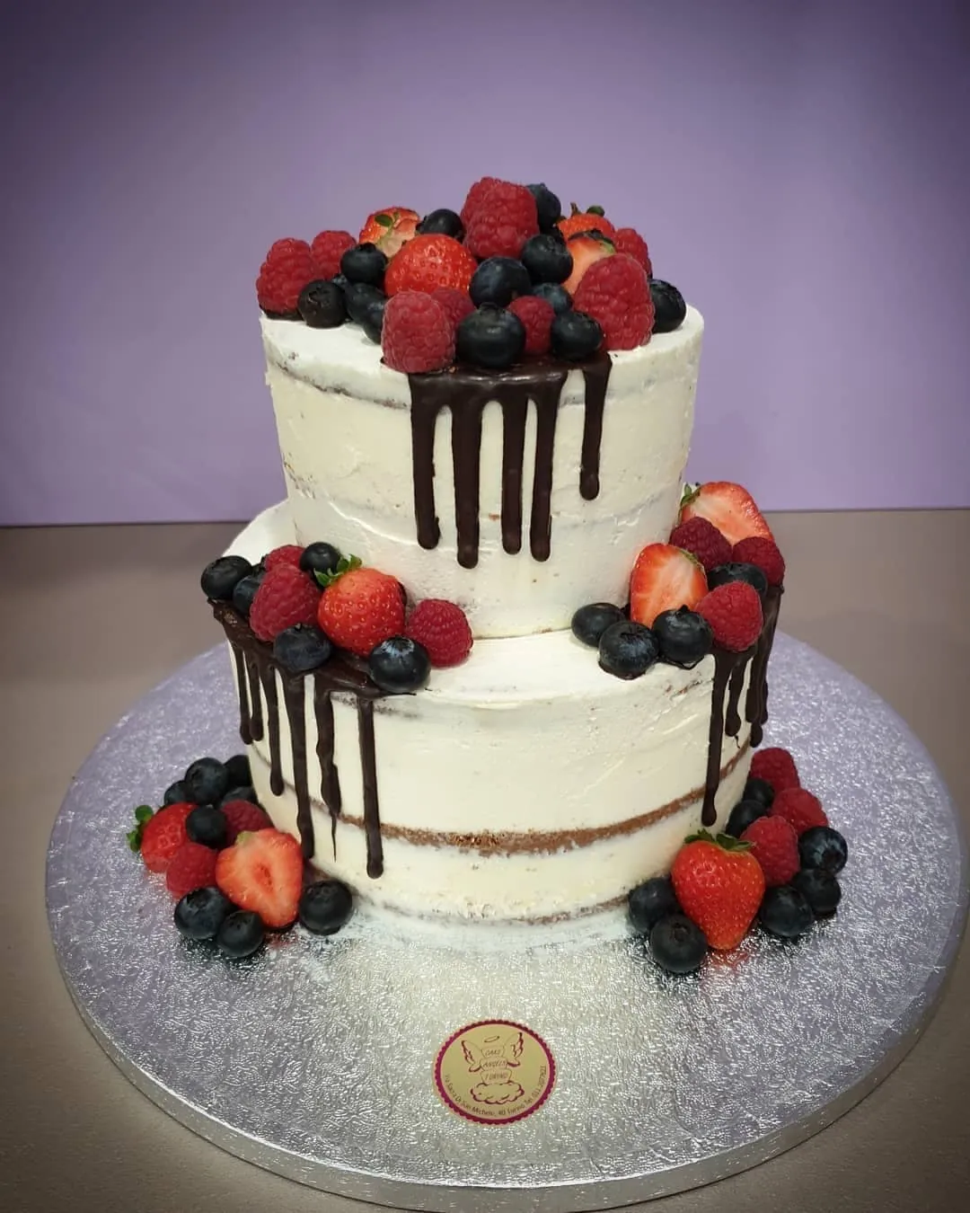 Torta naked a due piani con colata di cioccolato fondente, fragole, lamponi e mirtilli